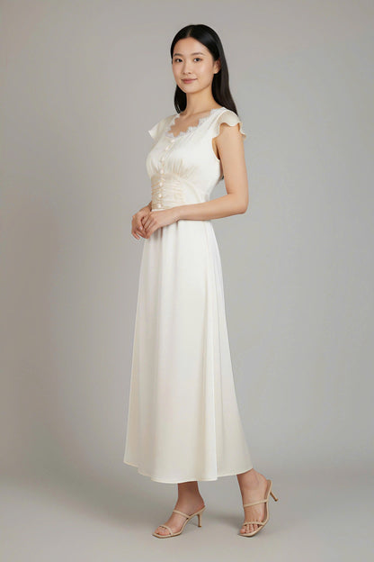 Woman wearing a white dress with lace details on a plain background