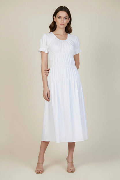 Woman wearing a white dress against a plain background