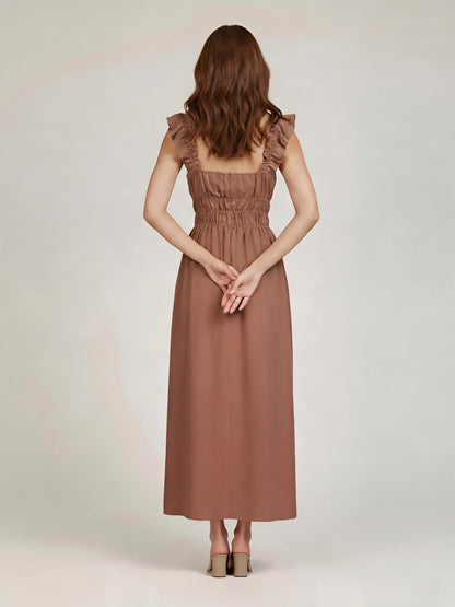 Woman wearing a brown dress with ruffled shoulders on a white background