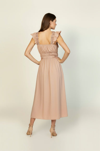 Woman wearing a beige dress with ruffled sleeves on a white background