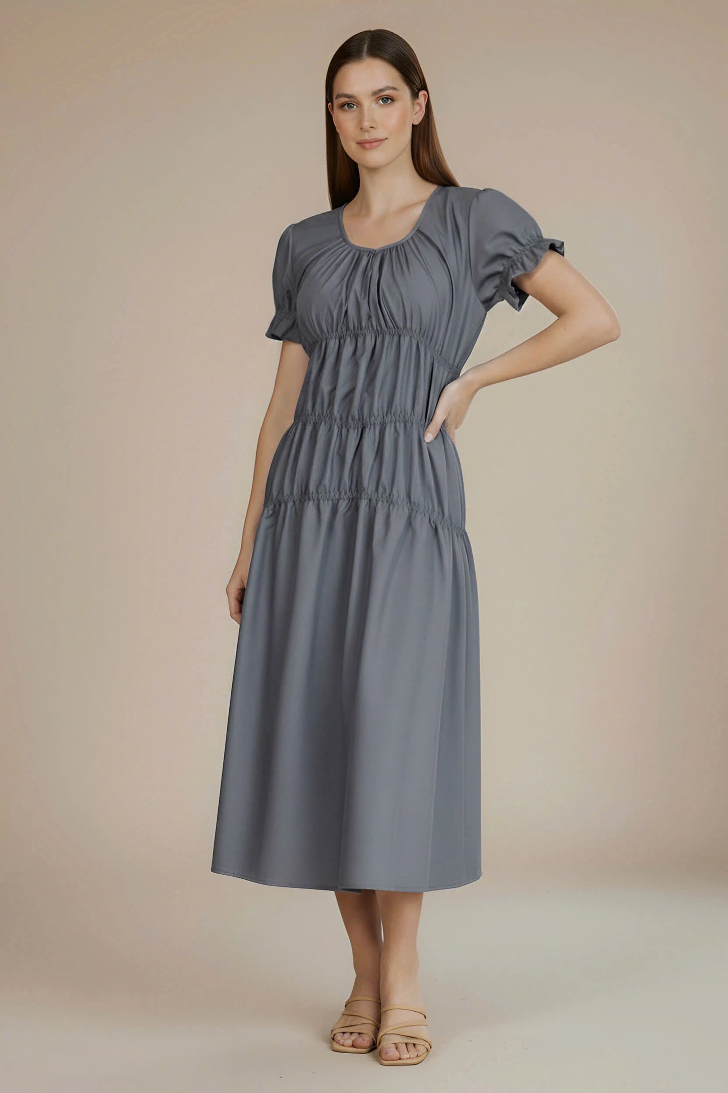 Woman wearing a gray dress against a beige background